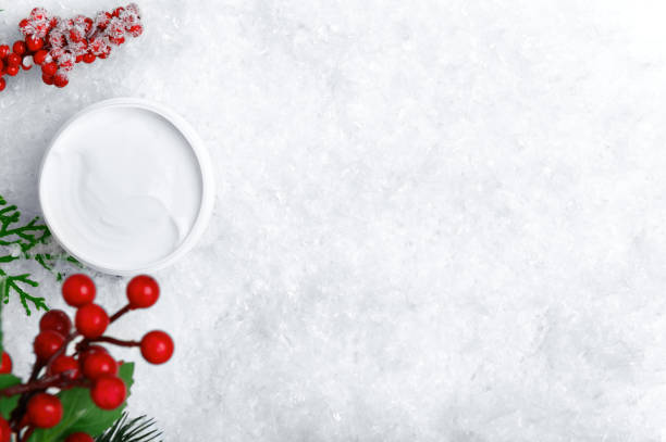 istock Open cream jar on white snow top view background. Bodycare balm container with mistletoe berries decorative flat lay backdrop. Winter season cosmetics blank advertisement with text space 1192700406