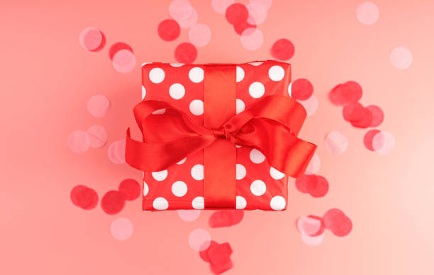 istock Single red gift box with red confetti on pink background top view 1192701994