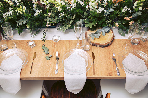 Summer holiday table set up. Elegant table setting with white dishes on a white linen tablecloth. Fruits, drinks in crystal glasses. Table set for outdoor eating in the garden. Top view
