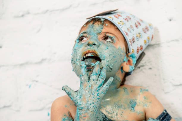 istock smashcake session, first cake of a 3-year-old boy with multiple disabilities. enjoying a lot while eating and getting dirty with blue cream 1192707248