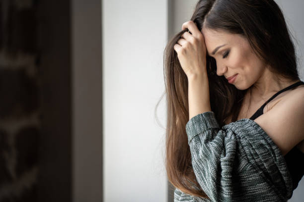 istock Pretty woman standing in front of window 1192707587