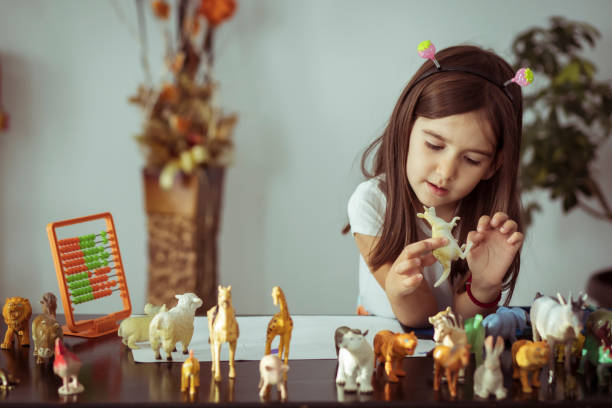 One little girl playing with toy animals in the living room stock photo