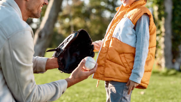 sostiere tuo figlio. padre insegna al figlio baseball nel parco in una giornata di sole - softball baseball glove sports equipment outdoors foto e immagini stock