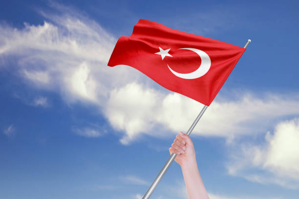 mano femenina está agitando la bandera turca contra el cielo azul con las nubes - turquia bandera fotografías e imágenes de stock