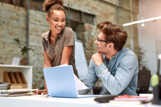 istock Work hard stay positive. Young colleagues looking at document and discussing something with smile while working together in the creative office 1192721521