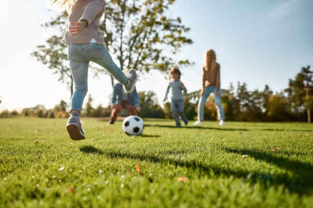 dove inizia il divertimento in famiglia. famiglia felice che gioca con una palla sul prato - ball horizontal outdoors childhood foto e immagini stock