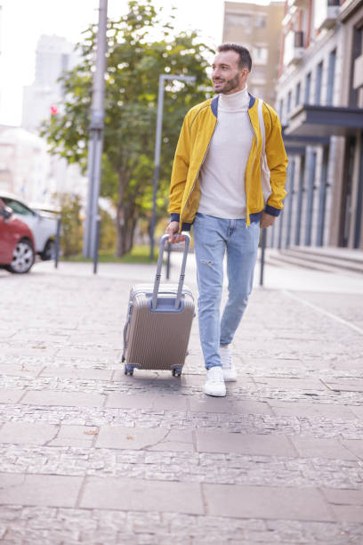 istock Handsome young male person wheeling his suitcase 1192722969