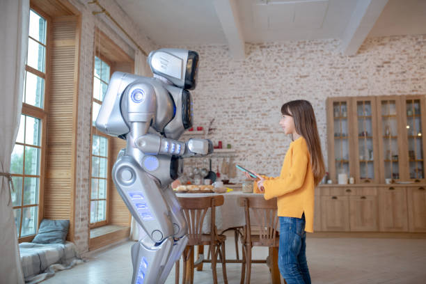 istock Robot and a cute girl talking in the kitchen 1192723125