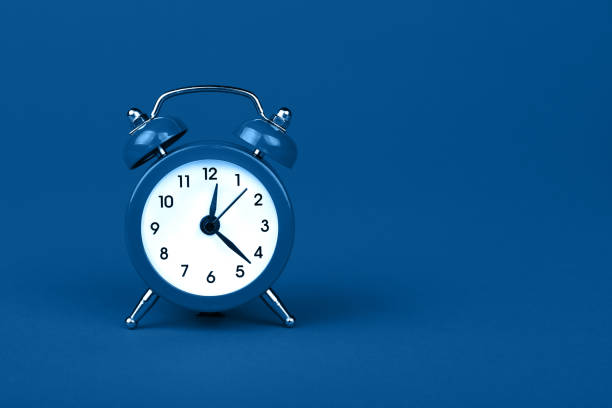 istock Close up one classic alarm clock over blue background 1192724264