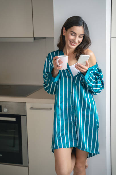 istock Happy lady using smartphone and drinking tea stock photo 1192724550
