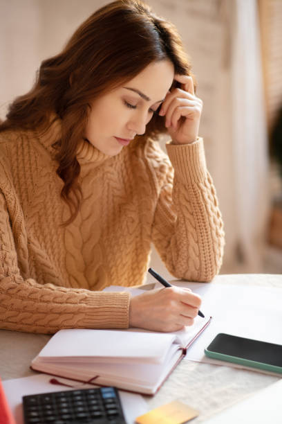 istock Dark-haired woman in knitted sweater making notes 1192726875