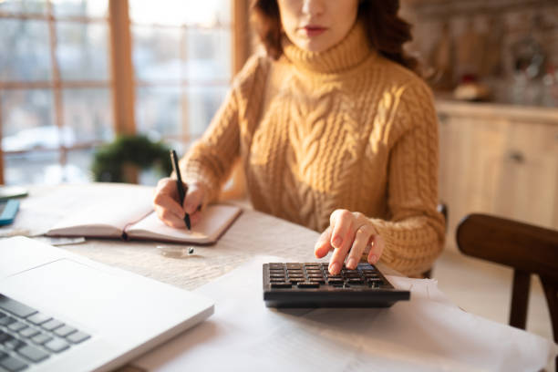 istock Dark-haired young woman in sweater making calculations 1192727140
