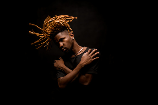 Afro american guy in black shirt waving his ginger dreadlocks