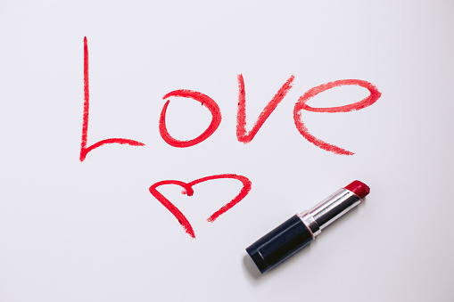 Love inscription, red lipstick on a white background. Painted heart