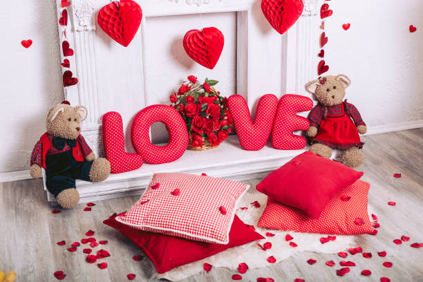 White fireplace in the interior with decorations and decorative elements on Valentine's Day. Rose petals and romantic toys