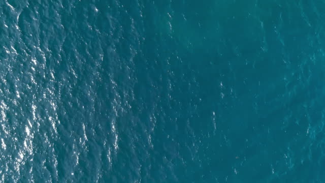 Aerial top down view from high altitude of blue azure  turquoise sea water texture. The camera flies over the water, a view of the water surface. Background of the water surface. 4K aerial view