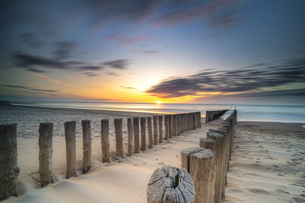 istock Groynes and wave breakers in a smooth sea just before sunset at a Dutch coast 1192733257