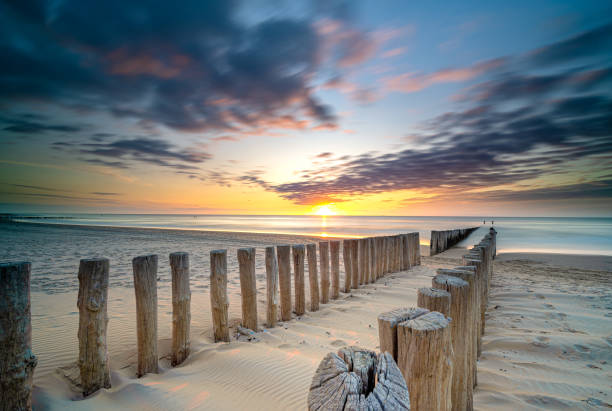 istock Groynes and wave breakers in a smooth sea just before sunset at a Dutch coast 1192733279