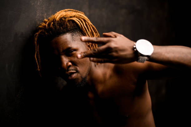 istock Naked black guy with blonde dreadlocks posing in the studio looking at camera showing finger gest 1192735401