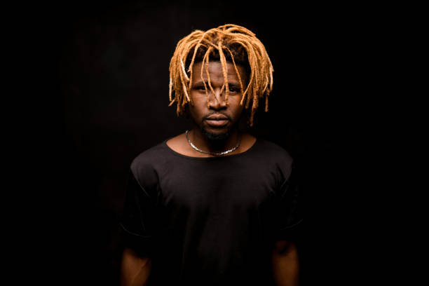 istock Black guy with blonde dreadlocks posing in the dark outfit looking at camera 1192735437