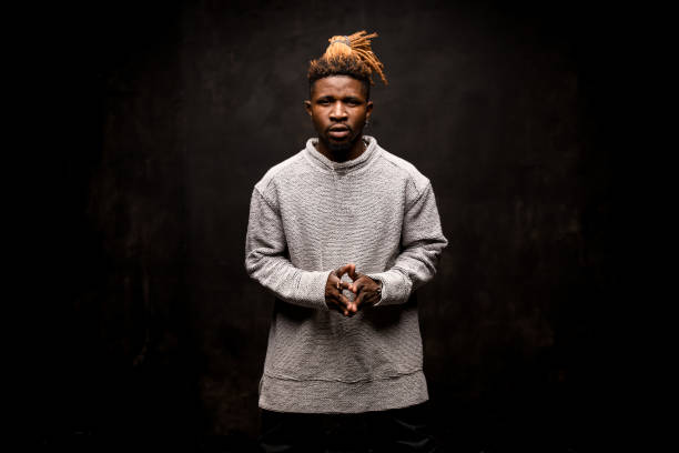 istock Black man with blonde dreadlocks posing holding fingers together looking at camera 1192735499