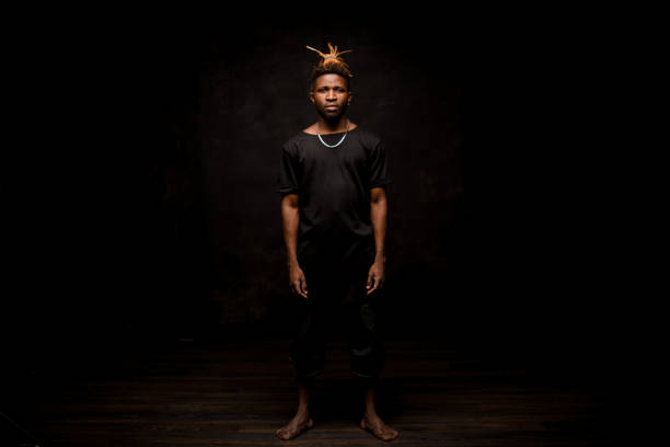 istock Black man with blonde dreadlocks posing in the dark outfit looking at camera 1192735550
