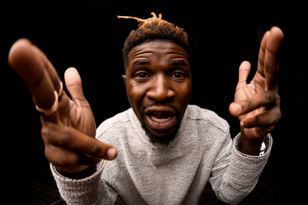 istock Fish-eye photo black man with blonde dreadlocks posing looking at camera makes pistols from fingers 1192736185