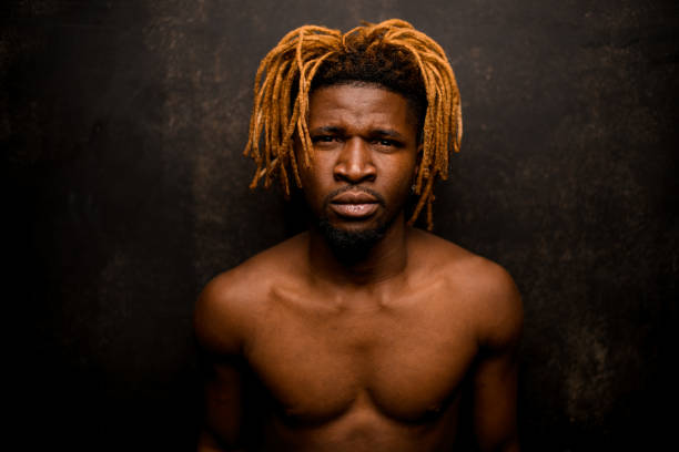 istock Naked black guy with blonde dreadlocks posing in the studio looking at camera 1192736266