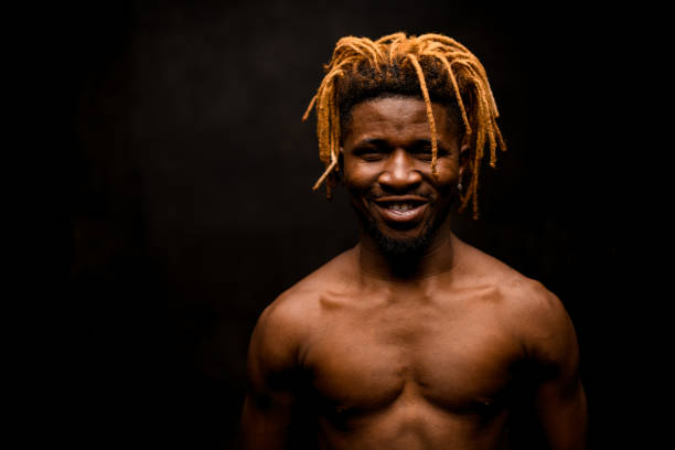 istock Smiling naked black guy with blonde dreadlocks posing in the studio looking at camera 1192736292
