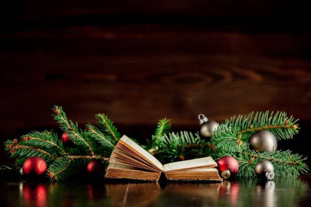 Old book and Christmas baubles on wooden table