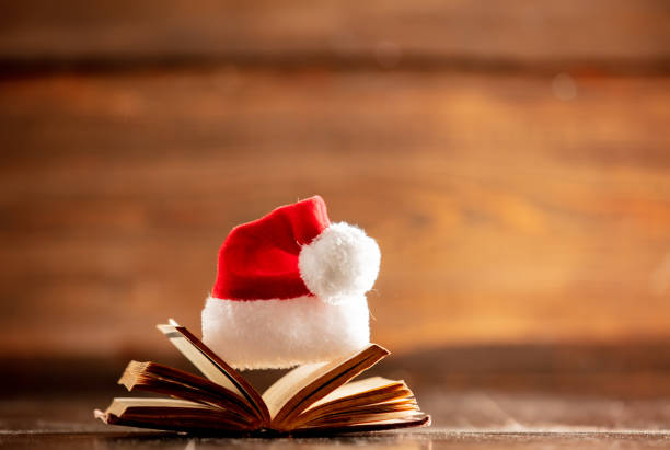 istock Christmas hat and open book on wooden table 1192737690