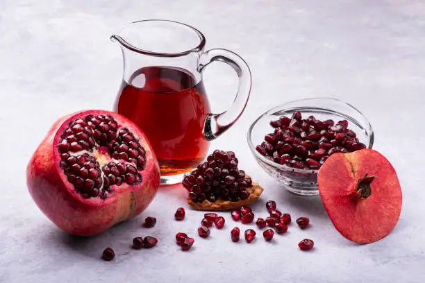 Juicy and fresh pomegranate, with seeds and pomegranate juice in a glass carafe