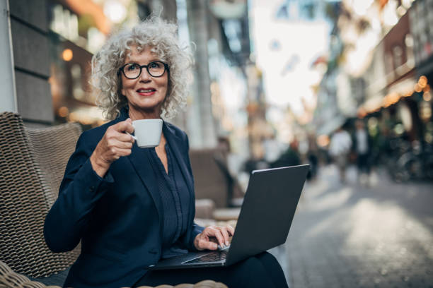 istock Beautiful senior woman working on laptop while drinking coffee 1192739455