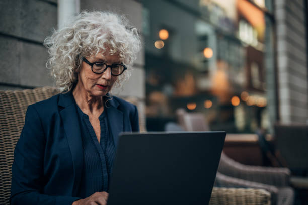 istock Beautiful senior woman working on laptop while drinking coffee 1192739475