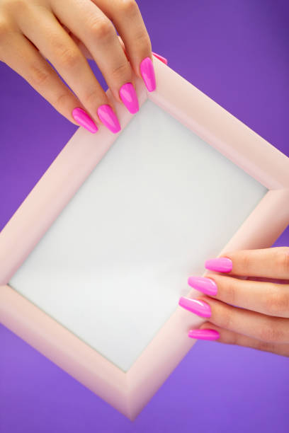 istock Manicure with Pink Nail-polish holding a blank Message frame 1192743717