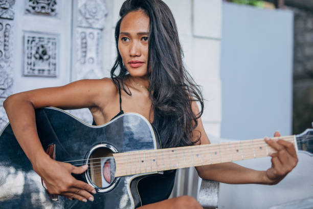 istock Young woman playing guitar on home terrace 1192744844