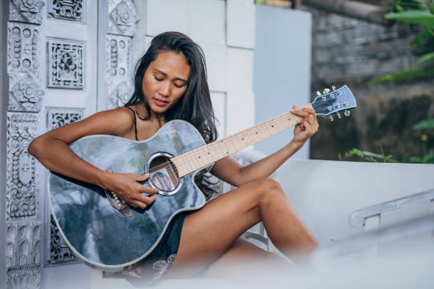 istock Young woman playing guitar on home terrace 1192744902