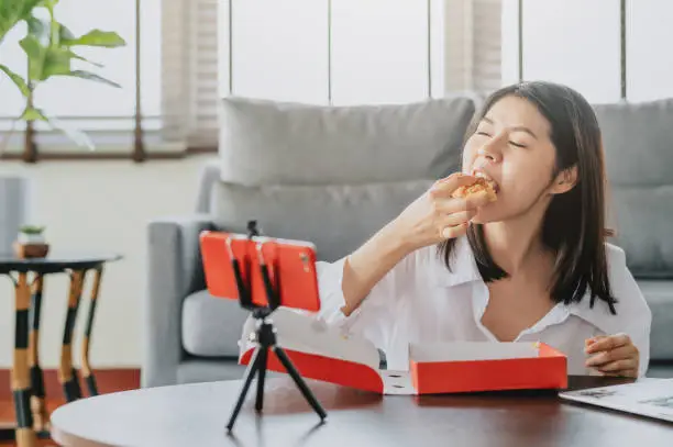 Photo of woman food blogger eating pizza while creating new content video