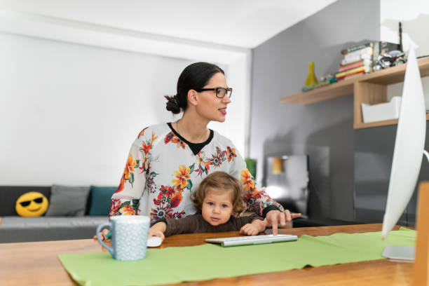 istock Young woman working at computer and holding her baby 1192746848