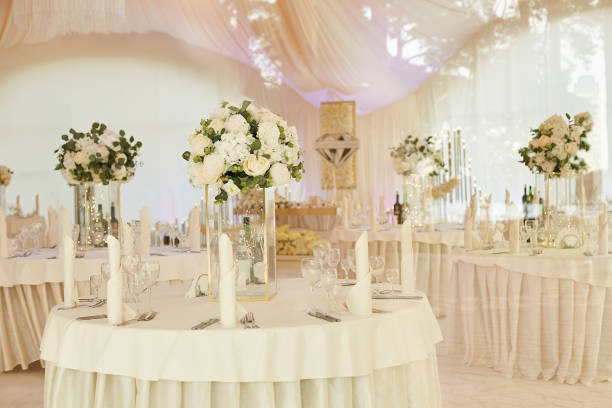 Banquet room with dining tables for guests during the wedding ceremony. The tent is decorated with white cloth. Banquet room with dining tables for guests during the wedding ceremony. The tent is decorated with white cloth. wedding hall stock pictures, royalty-free photos & images