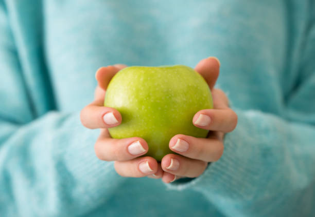 Hand comparing apple and orange for comparison concept