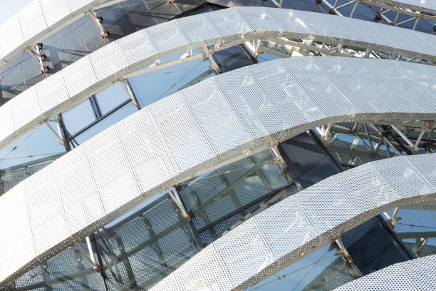 istock Diagonal view of high modern building construction with metal perforated panel with round holes and windows. Corner of modern building 1192759922