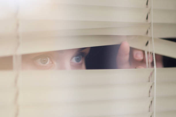 istock woman looking through the blinds, waiting for something 1192760125