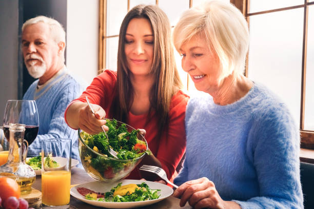 Family sitting at home, eating salad on dinner stock photo