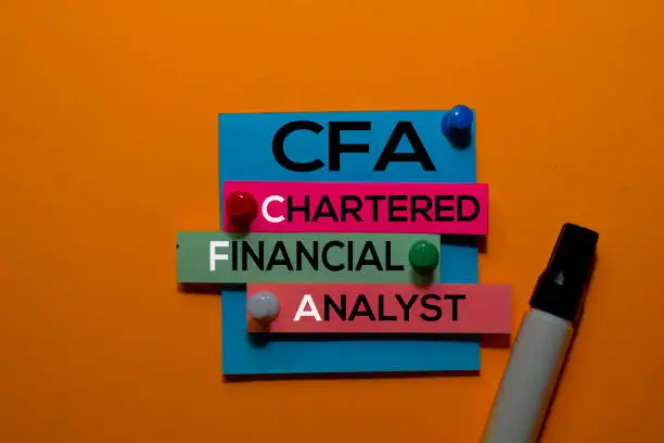 Photo of CFA. Chartered Financial Analyst acronym on sticky notes. Office desk background