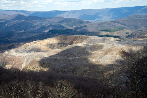 Open coal mine between Virginia and Kentucky.  Clouds overhead creating shadows.  Appalachian Mountains in the background.