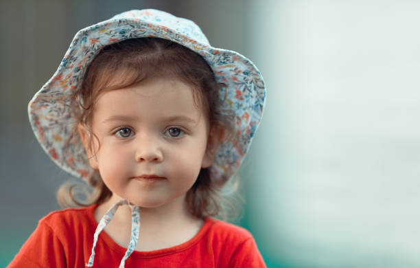 Baby Girl Posing Looking Seriously At The Camera Stock Photo - Download  Image Now - Bonnet - Hat, Child, 2-3 Years - iStock