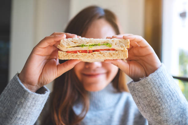 vrouw het houden van een stuk van volkoren sandwich bedekken haar ogen​​​ foto