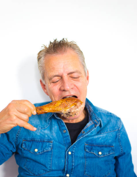 istock Senior Man Eating Turkey Leg, White Background 1192791402