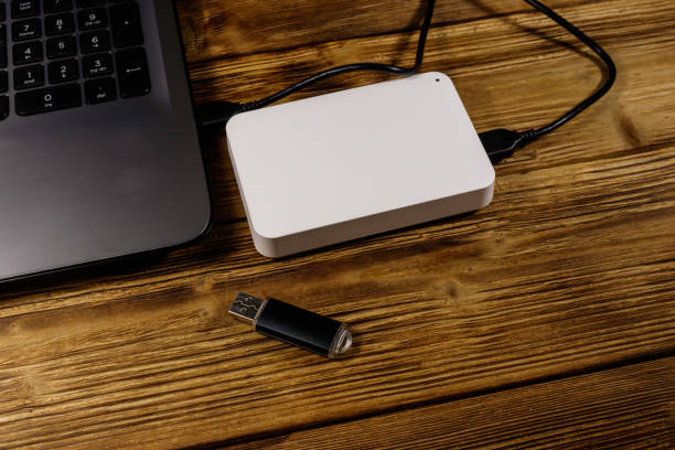 istock External HDD connected to laptop computer and USB flash drive on a wooden desk. Concept of data storage 1192802314